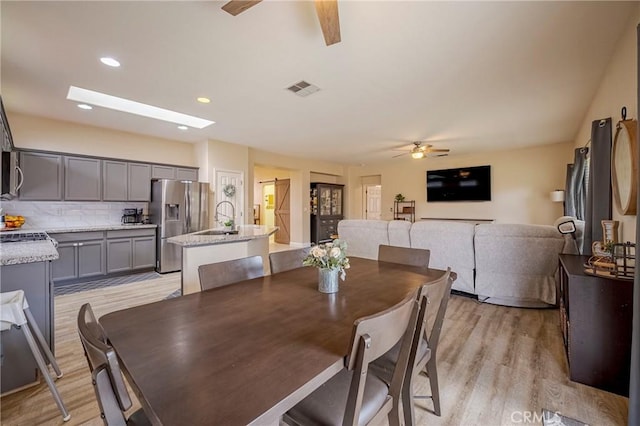 dining area featuring light hardwood / wood-style flooring, ceiling fan, and sink