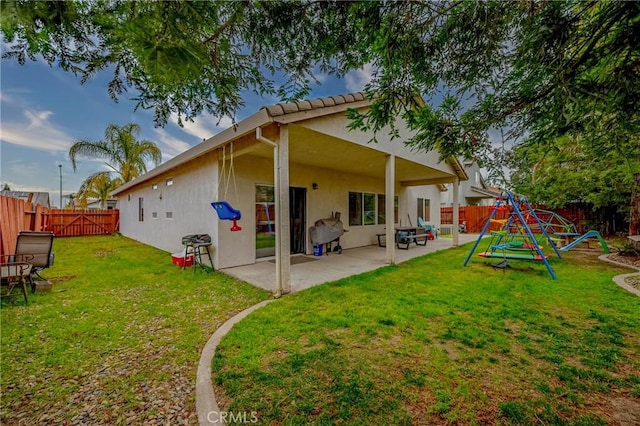 rear view of house with a playground, a yard, and a patio