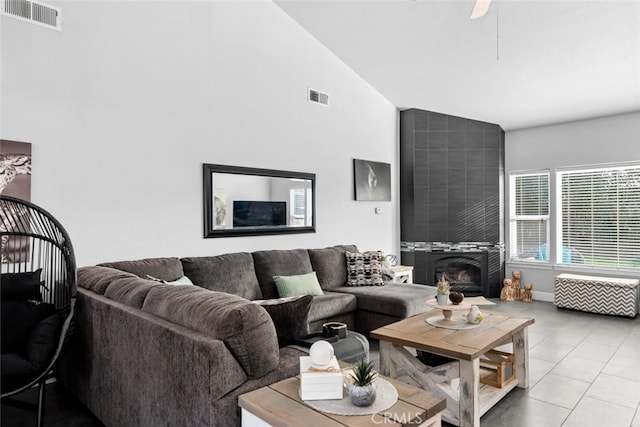 living room with lofted ceiling, a tile fireplace, visible vents, and light tile patterned flooring