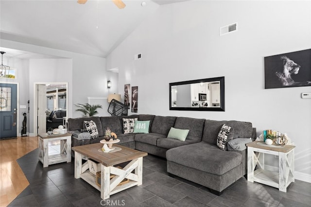 living area with high vaulted ceiling, visible vents, baseboards, and ceiling fan with notable chandelier