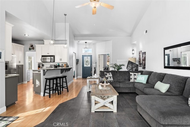 living area with dark wood-style floors, visible vents, high vaulted ceiling, and ceiling fan