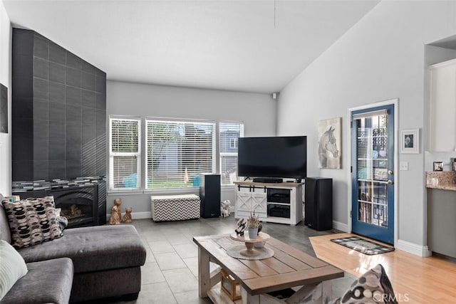 living area with baseboards, a tiled fireplace, and light tile patterned flooring