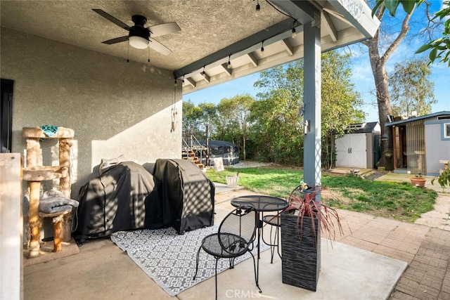 view of patio / terrace featuring area for grilling, a shed, an outdoor structure, and a ceiling fan