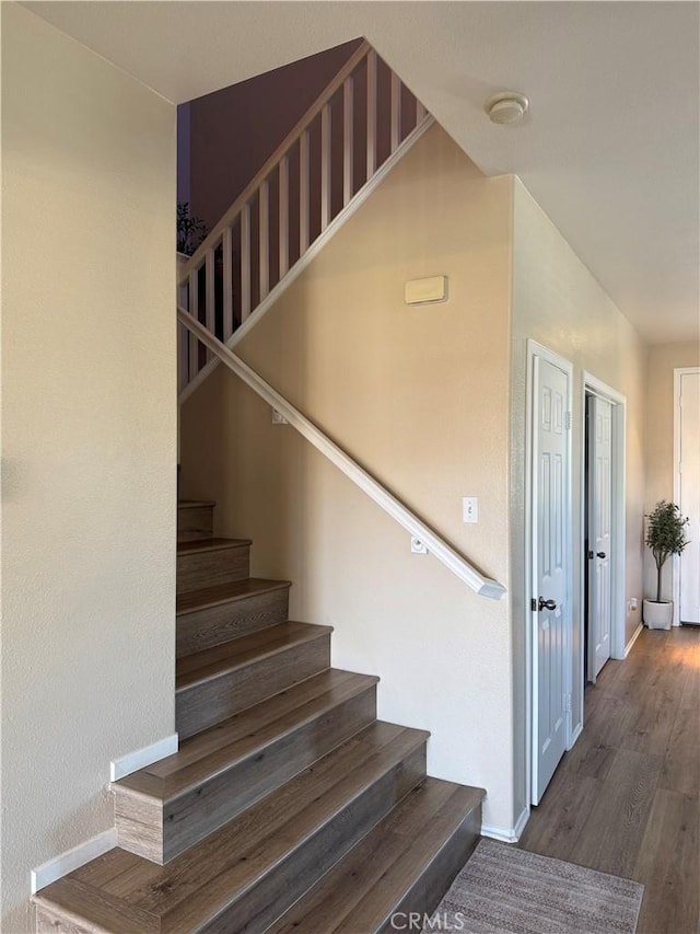 staircase featuring wood finished floors and baseboards