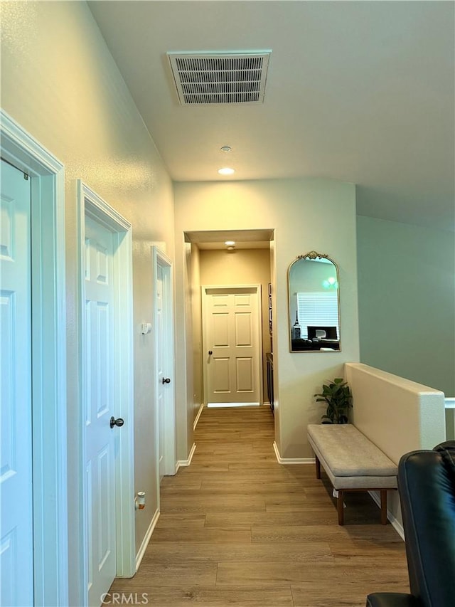 hallway with light wood-style flooring, visible vents, and baseboards