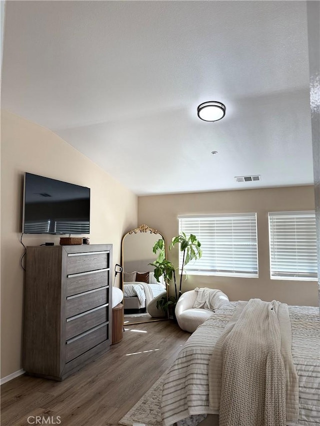 bedroom featuring lofted ceiling, visible vents, and dark wood finished floors