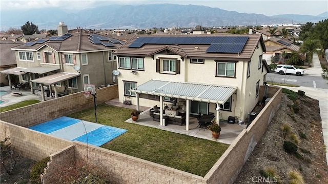 rear view of property featuring a patio, an outdoor hangout area, roof mounted solar panels, a residential view, and a fenced backyard