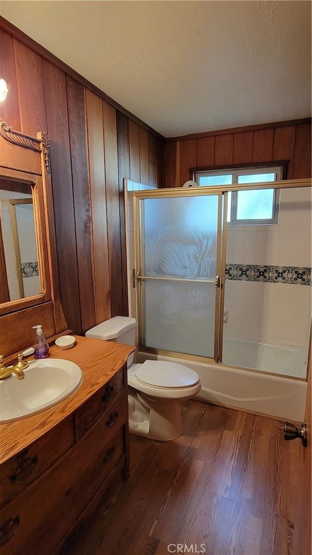 1239 Yosemite Dr, Lake Arrowhead, CA 92352 - bathroom featuring wood finished floors, toilet, vanity, bath / shower combo with glass door, and wood walls