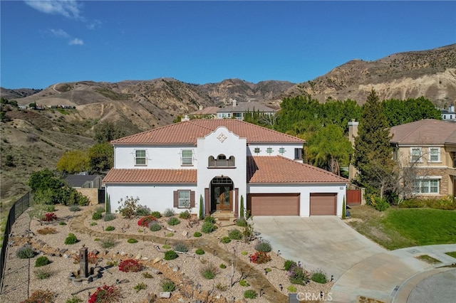 mediterranean / spanish-style house featuring driveway, a tiled roof, an attached garage, fence, and stucco siding