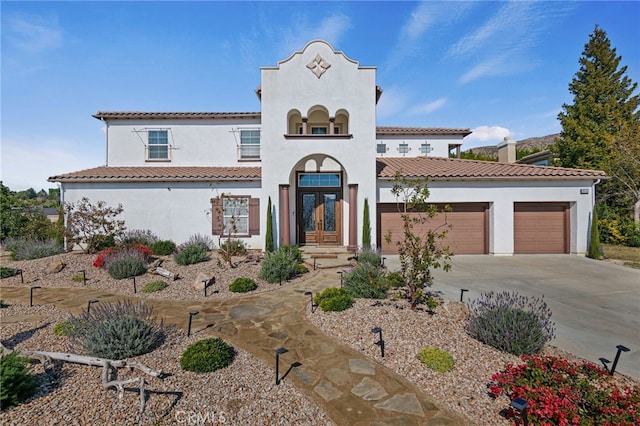 mediterranean / spanish home with a garage, french doors, concrete driveway, and stucco siding