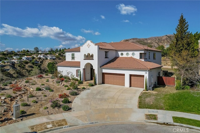 mediterranean / spanish home featuring an attached garage, fence, a tiled roof, driveway, and stucco siding