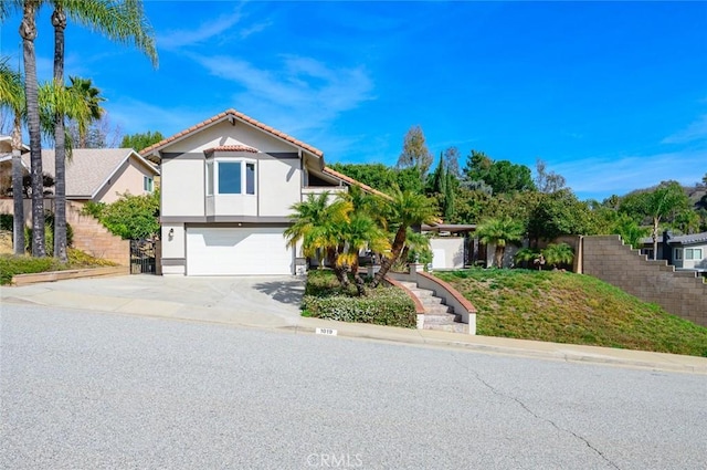 view of front of property with concrete driveway, an attached garage, a tile roof, and stucco siding