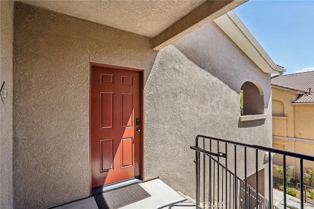 entrance to property featuring a balcony and stucco siding