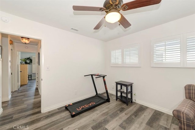 workout area featuring visible vents, ceiling fan, baseboards, and wood finished floors