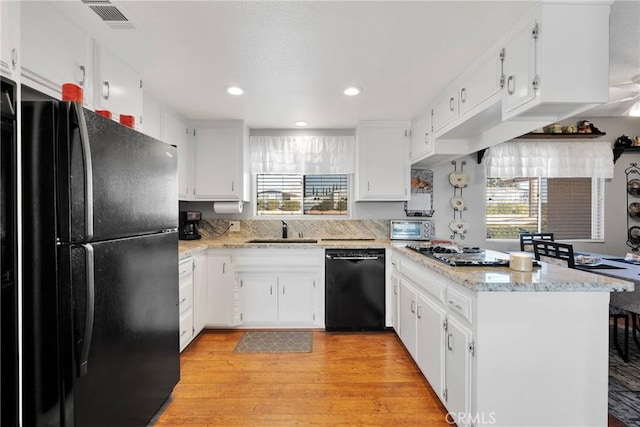 kitchen featuring white cabinets, sink, black appliances, and kitchen peninsula