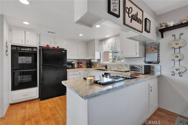 kitchen featuring sink, kitchen peninsula, black appliances, and white cabinets