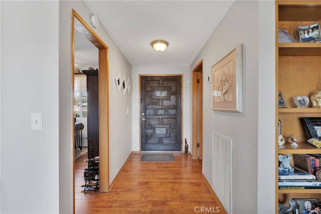 entryway with light hardwood / wood-style floors and a textured ceiling