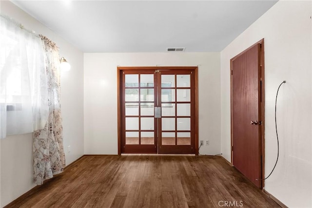unfurnished room featuring french doors, visible vents, and wood finished floors