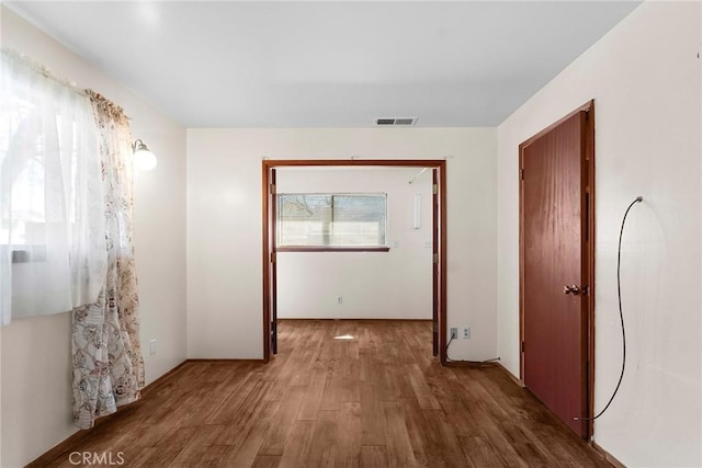 hall with visible vents and wood finished floors