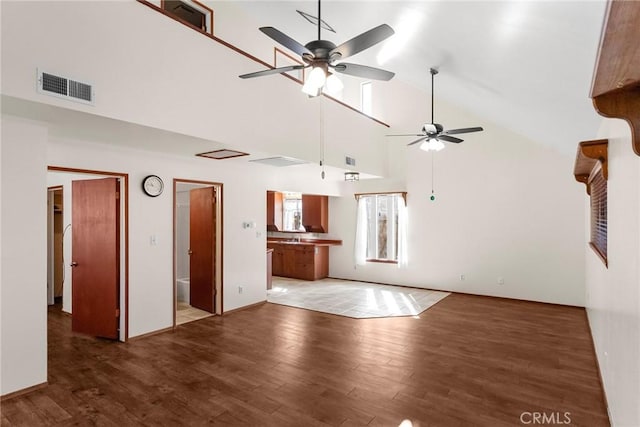 unfurnished living room with high vaulted ceiling, light wood-type flooring, and visible vents