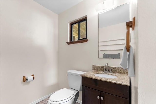 half bathroom featuring vanity, toilet, and baseboards