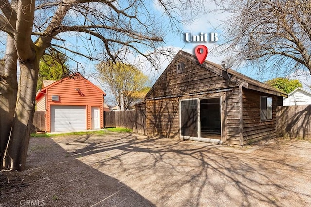 exterior space featuring a detached garage, fence, and an outdoor structure