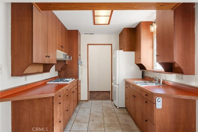 kitchen featuring range hood, light tile patterned floors, visible vents, a sink, and white appliances