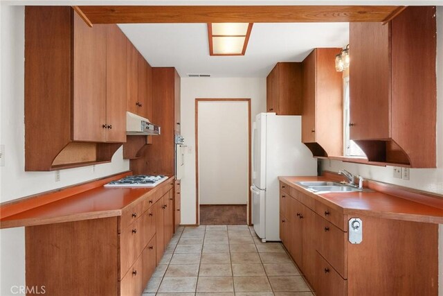 kitchen with white appliances, light tile patterned floors, exhaust hood, a sink, and visible vents