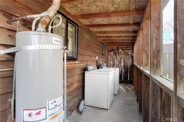 basement with washer and clothes dryer, wood walls, and gas water heater