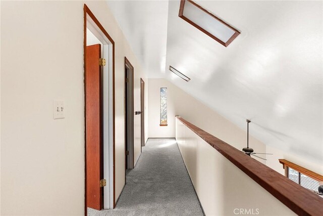 corridor with vaulted ceiling, an upstairs landing, and carpet floors