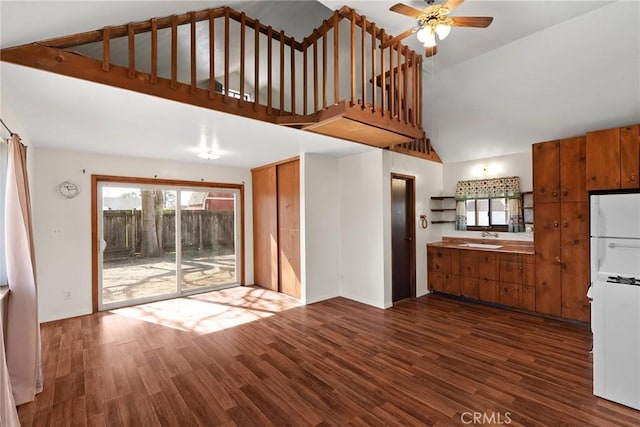 interior space with dark wood-type flooring, a sink, freestanding refrigerator, a ceiling fan, and brown cabinets
