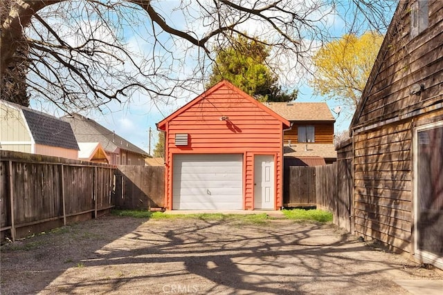 detached garage featuring fence and driveway