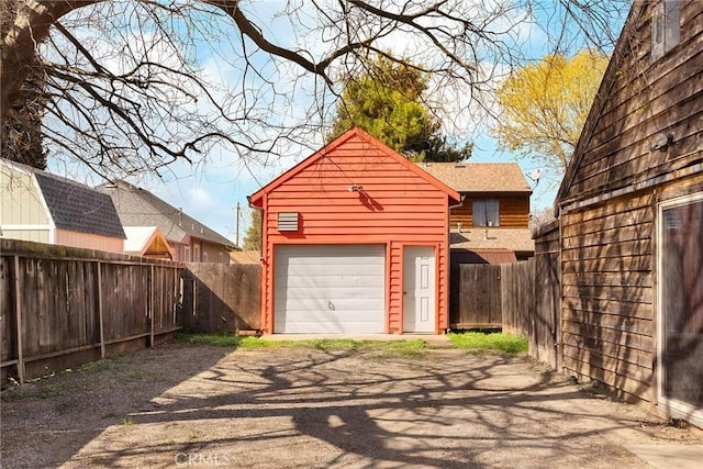 garage with fence and dirt driveway