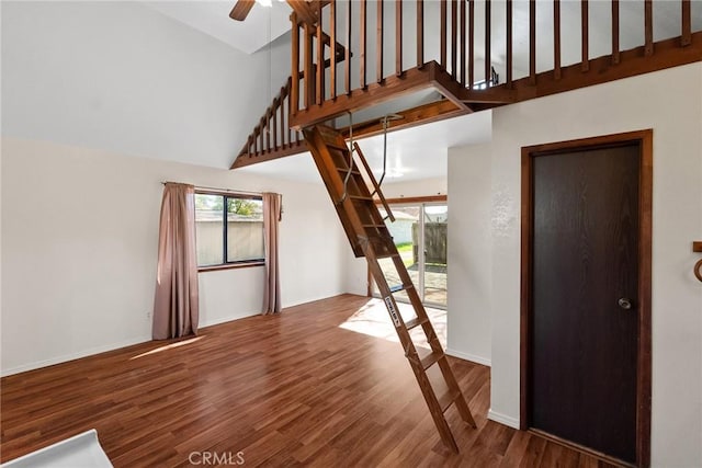 interior space featuring a high ceiling, baseboards, wood finished floors, and a ceiling fan