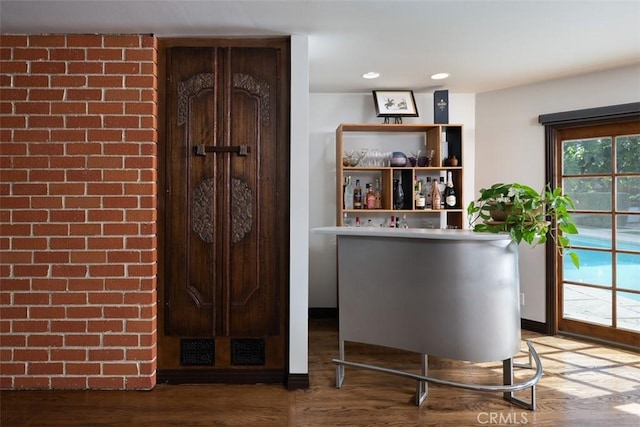 bar featuring baseboards, a bar, wood finished floors, and recessed lighting