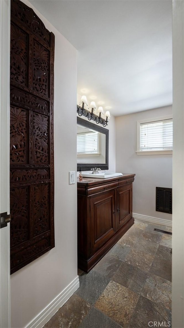 bathroom featuring visible vents, baseboards, stone finish flooring, and vanity