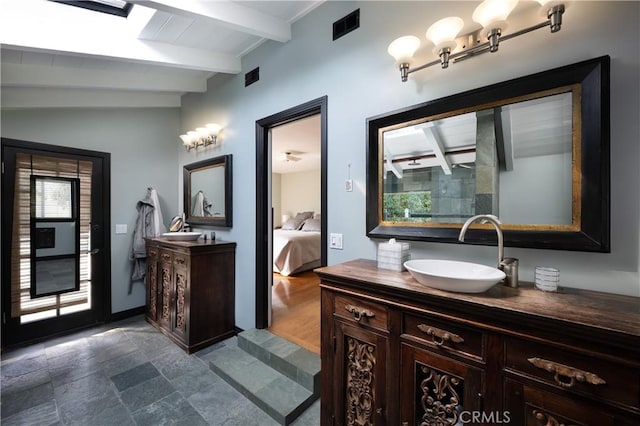 ensuite bathroom with stone tile floors, two vanities, visible vents, a sink, and ensuite bath