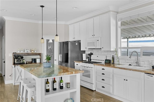 kitchen featuring white appliances, light stone countertops, a kitchen island, sink, and white cabinetry