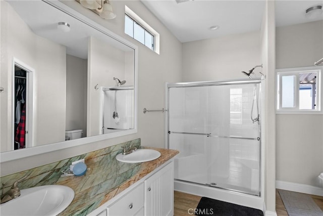 bathroom with an enclosed shower, vanity, toilet, and a wealth of natural light