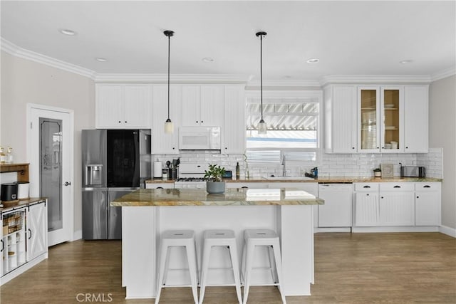 kitchen featuring white cabinetry, a kitchen island, white appliances, light stone counters, and pendant lighting