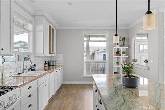 kitchen with white gas range oven, sink, pendant lighting, and white cabinets