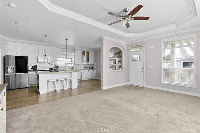 interior space with crown molding, ceiling fan, and a raised ceiling