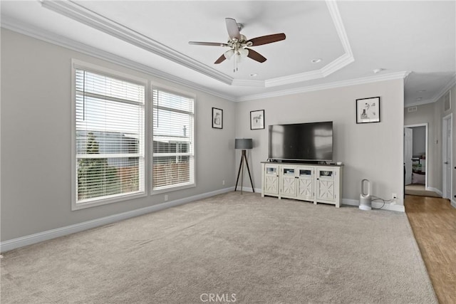 unfurnished living room featuring crown molding, light colored carpet, ceiling fan, and a raised ceiling