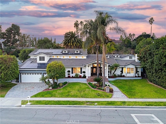 view of front of house with a yard, solar panels, and a garage