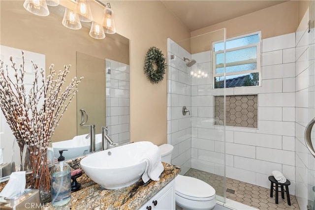 bathroom featuring toilet, tiled shower, and vanity