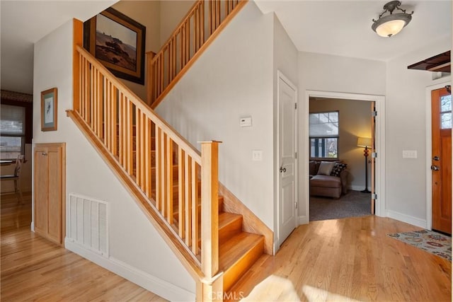 stairway featuring wood finished floors, visible vents, and baseboards