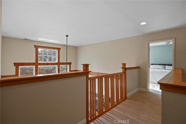 hall featuring carpet floors, recessed lighting, baseboards, and an upstairs landing