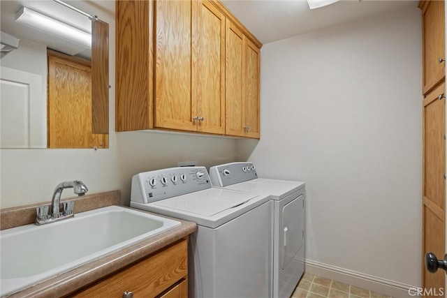 clothes washing area featuring separate washer and dryer, a sink, cabinet space, and baseboards