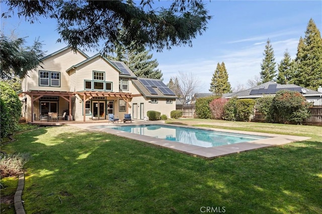 rear view of property with a fenced in pool, roof mounted solar panels, a fenced backyard, and a pergola