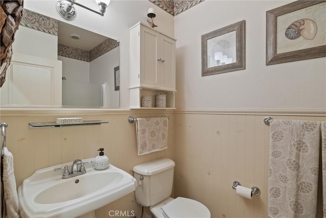 bathroom featuring a wainscoted wall, a sink, and toilet